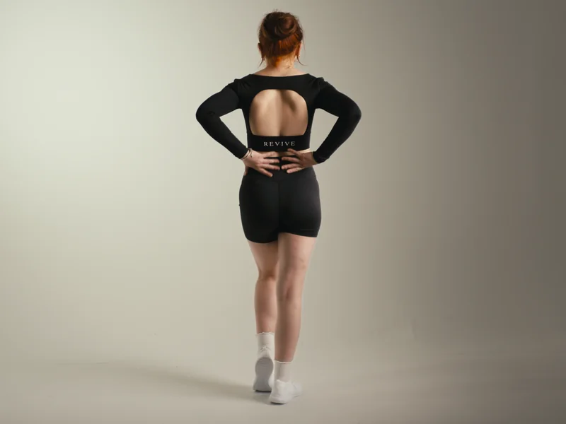 Revival still: model in REVIVE activewear facing away, grey studio background