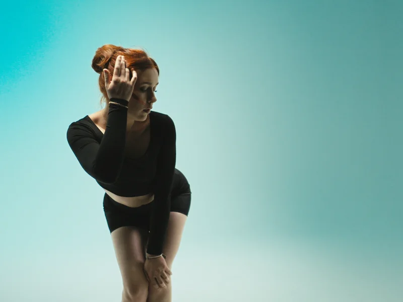 Revival still: model bending forward in REVIVE activewear, teal gradient background