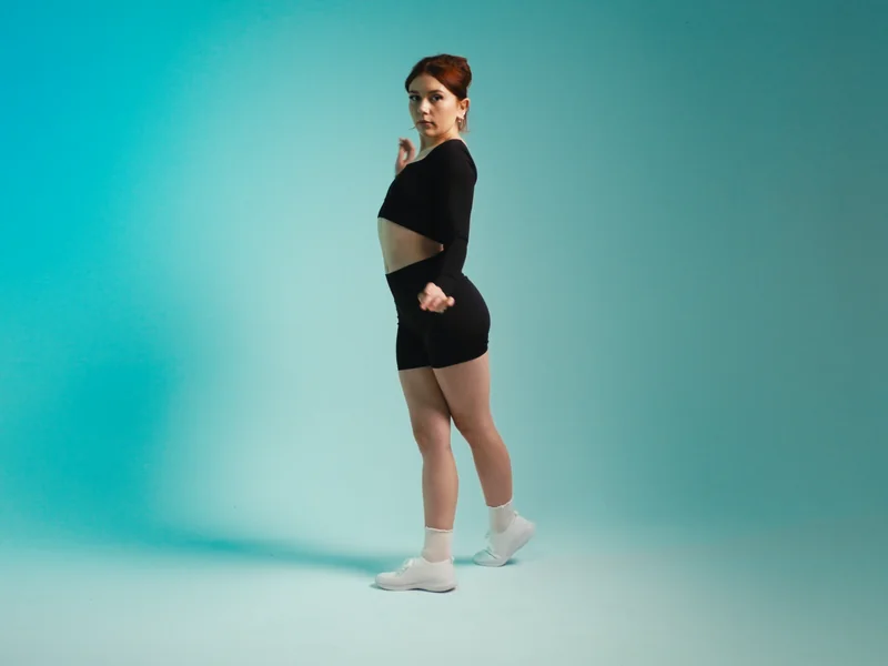 Revival still: model in side profile wearing REVIVE cut-out crop and shorts, teal background